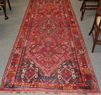 Lot 1365 - A Kashgai rug, the crimson field of tribal motifs framed by spandrel narrow borders, measures 310cm