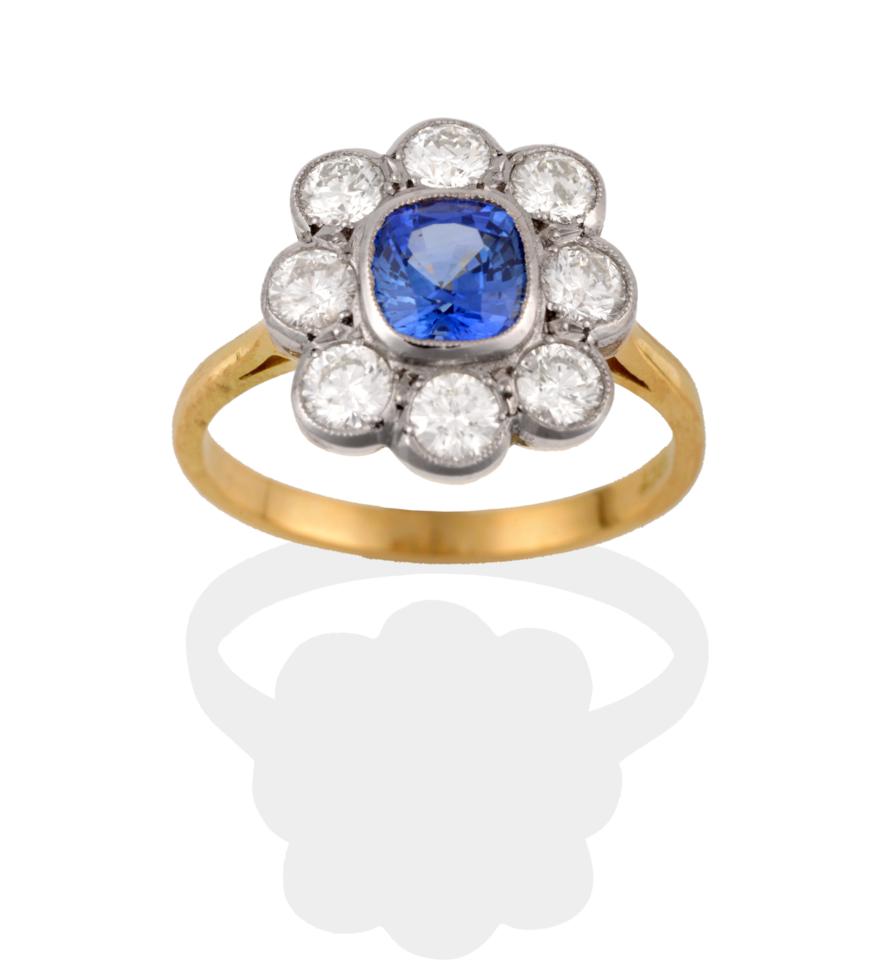Lot 2053 - A Sapphire and Diamond Cluster Ring, the cushion cut sapphire within a border of round...