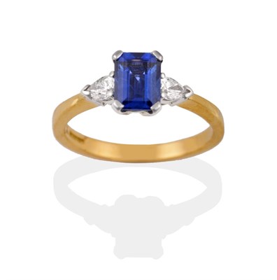 Lot 2058 - An 18 Carat Gold Sapphire and Diamond Three Stone Ring, the emerald-cut sapphire flanked by two...