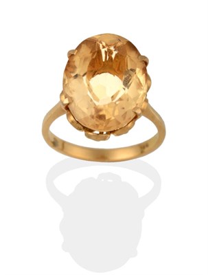 Lot 2064 - A Citrine Solitaire Ring, the oval cut citrine in a yellow claw setting to a tapered shoulder plain