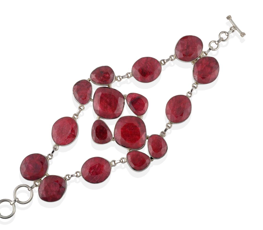 Lot 2073 - An Abstract Ruby Bracelet, mixed cut rubies in white rubbed over settings arranged in two...