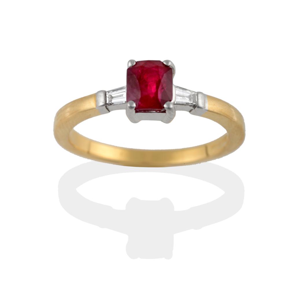 Lot 2076 - An 18 Carat Gold Ruby and Diamond Three Stone Ring, the modified emerald-cut ruby sits between...