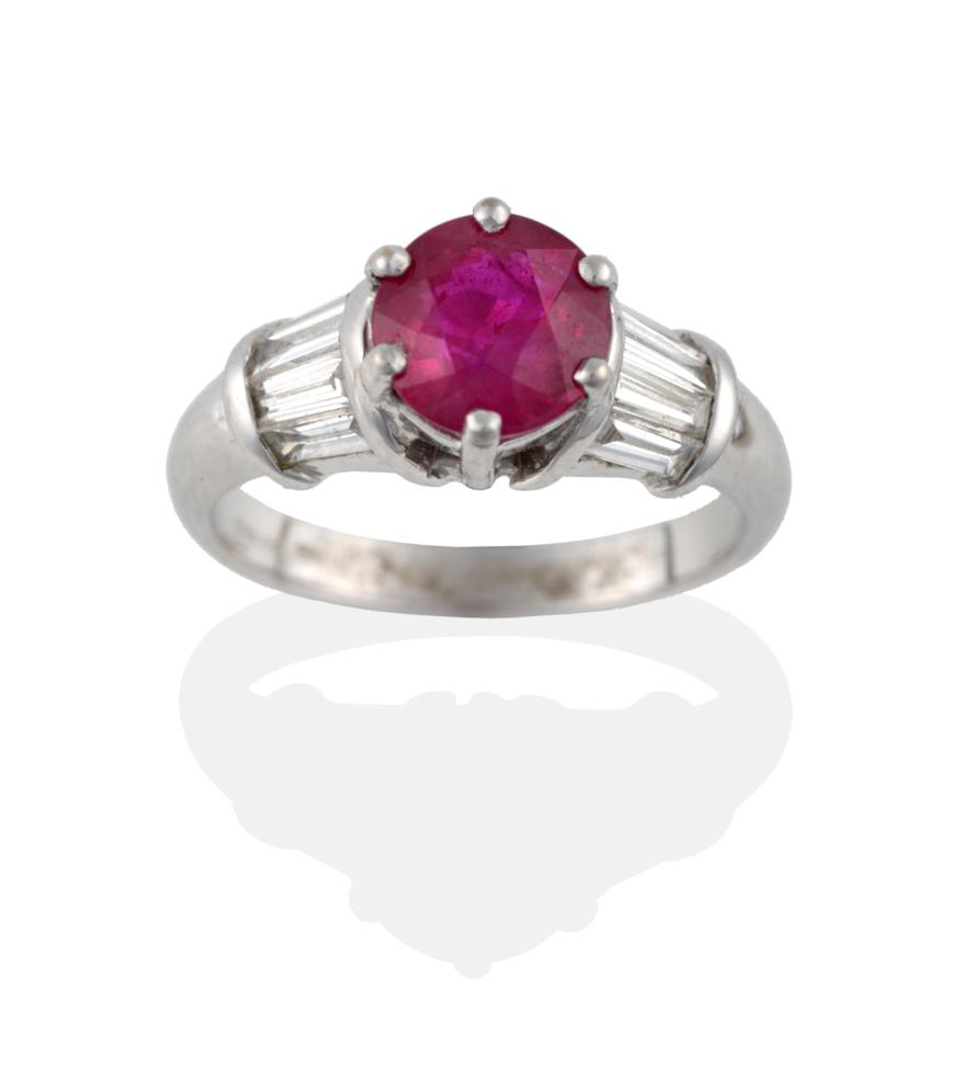 Lot 2078 - An 18 Carat White Gold Ruby and Diamond Ring, a round cut ruby claw set with tapered baguette...