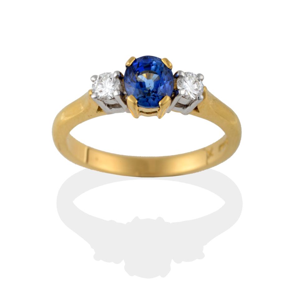 Lot 2091 - An 18 Carat Gold Sapphire and Diamond Three Stone Ring, the oval mixed cut sapphire between two...
