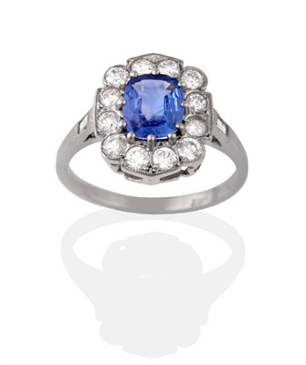Lot 2117 - A Sapphire and Diamond Cluster Ring, the cushion cut sapphire within a border of round...