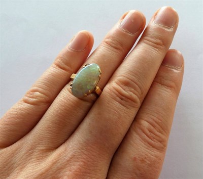 Lot 2149 - An Opal Ring, the oval cabochon opal in a yellow double claw setting to linear decorated...