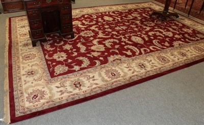 Lot 1362 - A large Indian carpet, the claret field with an allover design leafy vines enclosed by ivory...