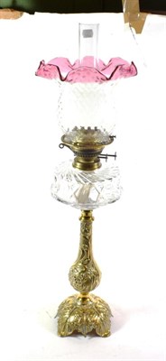 Lot 331 - A Victorian oil lamp, the cast bronze base decorated with leaves and flowers, with cut clear...