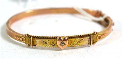 Lot 382 - A 9 carat gold hinged bangle with diamond set heart motif and thistle decoration
