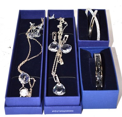 Lot 393 - Two Swarovski necklace and earring suites and two Swarovski bangles, all boxed