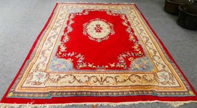 Lot 1255 - An Indian ''Savonnerie'' carpet, the blood red field with floral medallion enclosed by leafy...