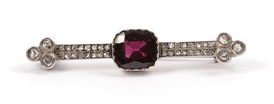 Lot 169 - A Garnet and Diamond Brooch, the cushion cut garnet in a crimped setting centres two parallel...