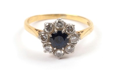 Lot 182 - An 18 Carat Gold Synthetic Sapphire and Diamond Cluster Ring, a round cut sapphire within a...