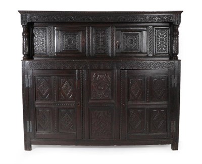 Lot 1675 - A Carved Oak Court Cupboard, the upper section with three carved panels with two cupboard...