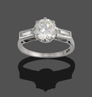 Lot 363 - A Diamond Solitaire Ring, the round brilliant cut diamond claw set between shoulders each inset...