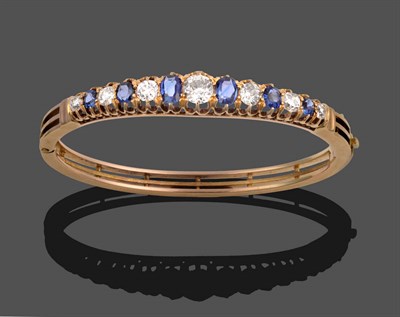 Lot 229 - A Sapphire and Diamond Bangle, circa 1880, six graduated oval cut sapphires alternate with...