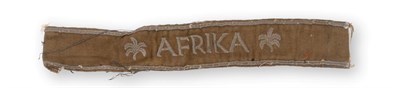 Lot 176 - A German Third Reich 'Afrika' Cuff Title, in khaki/tan cloth, machine embroidered in silver...