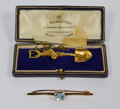 Lot 274 - A shovel and nugget brooch, stamped '18C', length 5.7cm, and a blue zircon bar brooch, stamped...