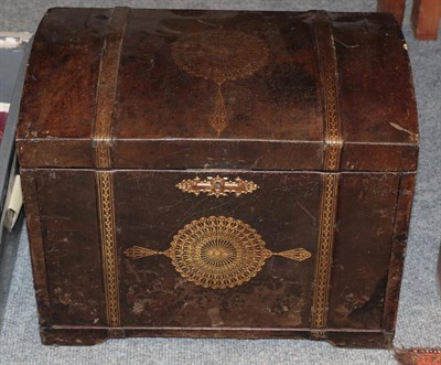 Lot 1027 - A brown leather and gilt tooled cabinet, in the form of a dome top trunk, with hinged lid enclosing