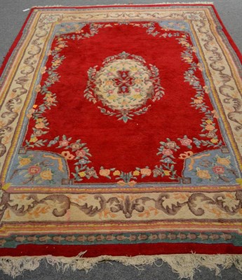 Lot 1148 - An Indian ''Savonnerie'' carpet, the blood red field with floral medallion enclosed by leafy...