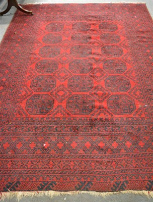 Lot 1153 - Afghan carpet, the crimson field with three columns of elephant foot guls, enclosed multiple...