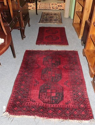 Lot 1160 - An Afghan rug, the claret field with three elephant foot guls, enclosed by triple borders, 150cm by