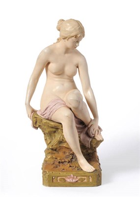 Lot 80 - A Royal Dux Porcelain Figure of a Bather, 1920's, sitting on a rocky outcrop with a pink towel on a