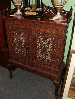 Lot 1240 - A late 19th century pierced hardwood side cabinet, with two panel doors, above two short...