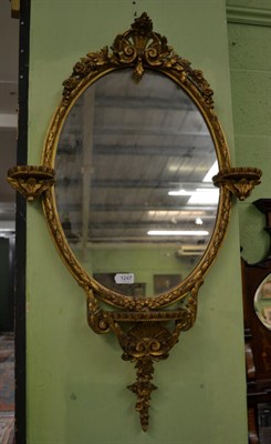 Lot 1247 - Late 19th/early 20th century gilt and gesso oval wall mirror with three small shelves, 90cm high