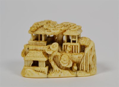 Lot 115 - A Japanese ivory netsuke, Meiji period, carved as figures and buildings in a rocky landscape,...