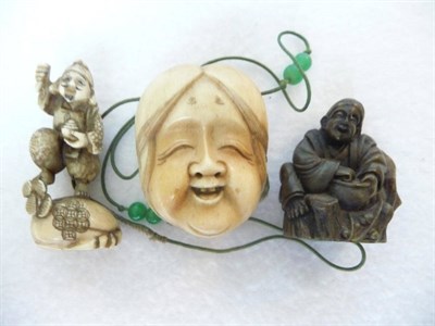 Lot 201 - A Japanese Horn Netsuke, 19th century, as a seated sage by a tree stump smiling and holding a...