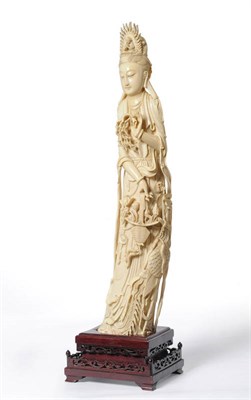 Lot 241 - A Chinese Carved Ivory Figure of Guanyin, circa 1930, standing with figural headdress and flowering