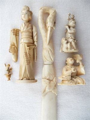 Lot 242 - A Japanese Carved Ivory Figure of a Boy, circa 1930, kneeling holding a bird in one hand, a cup...