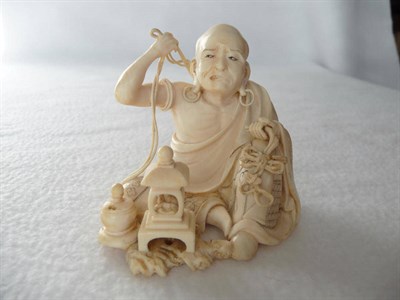 Lot 250 - A Japanese Carved Ivory Figure of a Seated Man, Meiji period (1868-1912), with loop earrings...