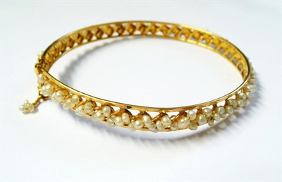 Lot 294 - A Seed Pearl Bangle, the bangle with faceted edges, diagonally strung rows of freshwater seed...