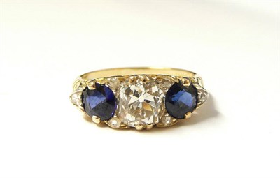 Lot 307 - A Diamond and Sapphire Ring, an old cut diamond flanked by two round cut sapphires, with rose...