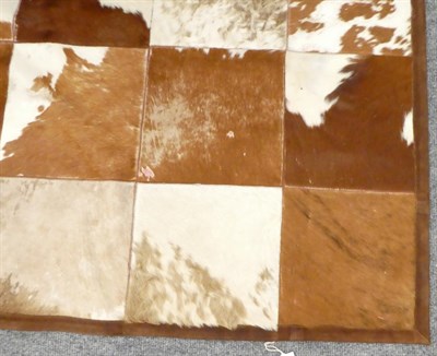 Lot 1076 - Hides/Skins: A Large Patchwork Cow Hide Rug, modern, constructed with square sections of cow...