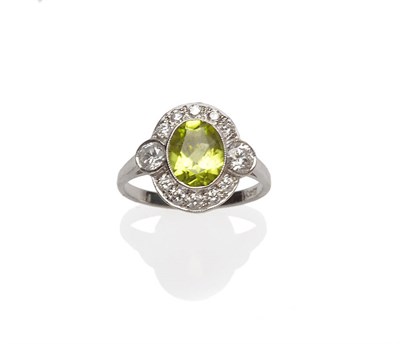 Lot 349 - A Peridot and Diamond Cluster Ring, an oval cut peridot within a border of round brilliant cut...