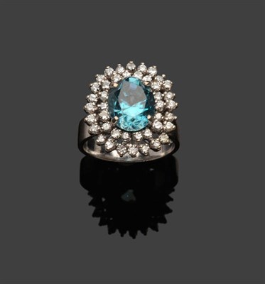 Lot 365 - A Blue Zircon and Diamond Cluster Ring, the oval mixed cut zircon within a double undulating border