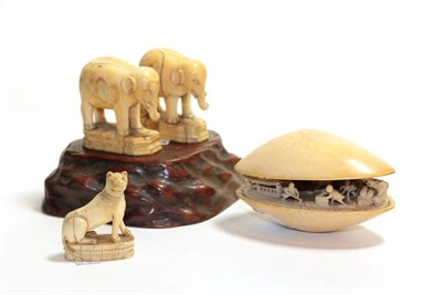 Lot 59 - A carved ivory shell on stand, including three carved tusk figures of elephants and a lion
