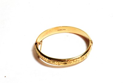 Lot 85 - A 9 carat gold half engraved bangle, inner measurements 6cm by 5.4cm