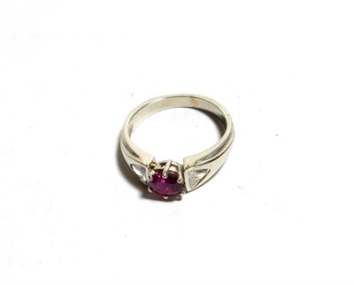 Lot 111 - A ruby and diamond ring, an oval cut ruby in a white claw setting, flanked by trilliant cut diamond