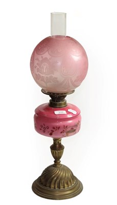 Lot 215 - A Victorian brass oil lamp with pink and floral decorated glass reservoir