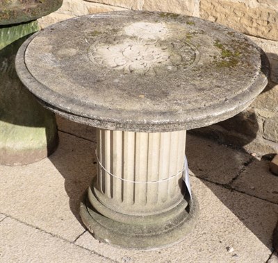 Lot 1106 - A weathered composition pedestal garden table, the circular top on a fluted column base
