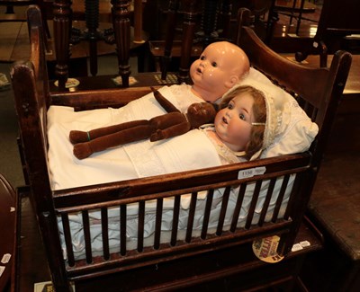 Lot 1156 - Late 19th century child's crib containing two Armand Marsille and a Nora Wellings style doll