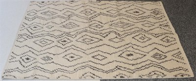 Lot 1299 - Modernist Moroccan Hand-Knotted Rug, the ivory field of diamond medallions flanked by zigzags,...