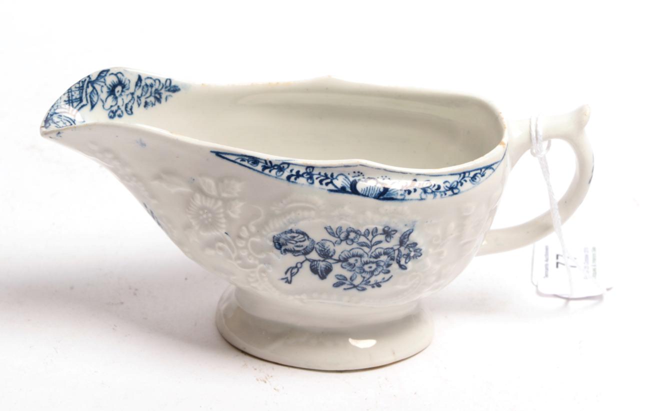 Lot 77 - A Lowestoft porcelain sauceboat, circa 1775, printed in underglaze blue with flower sprays...