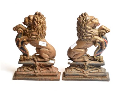 Lot 100 - Pair of cast iron door stops in the form of lions bearing shields