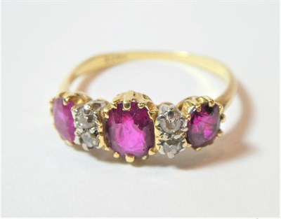 Lot 194 - A ruby and diamond ring, three oval cut rubies spaced by pairs of eight-cut diamonds, in yellow and