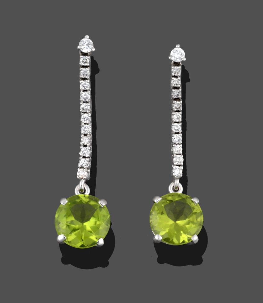 Lot 221 - A Pair of Peridot and Diamond Drop Earrings, a round brilliant cut peridot suspended from an...